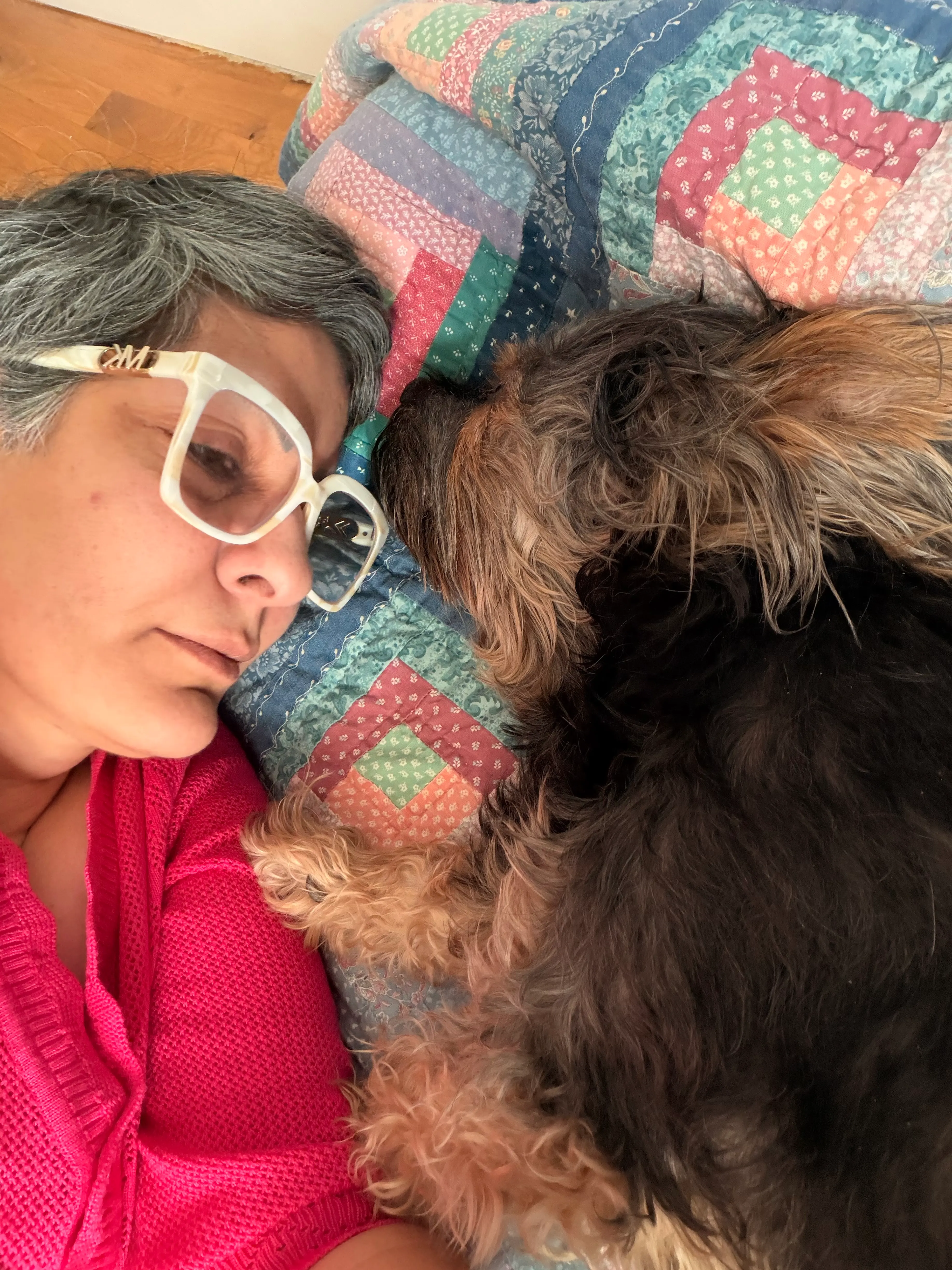 Claudia lying against a patchwork quilt, her cheek resting close to Pearl, who is curled up beside her face.