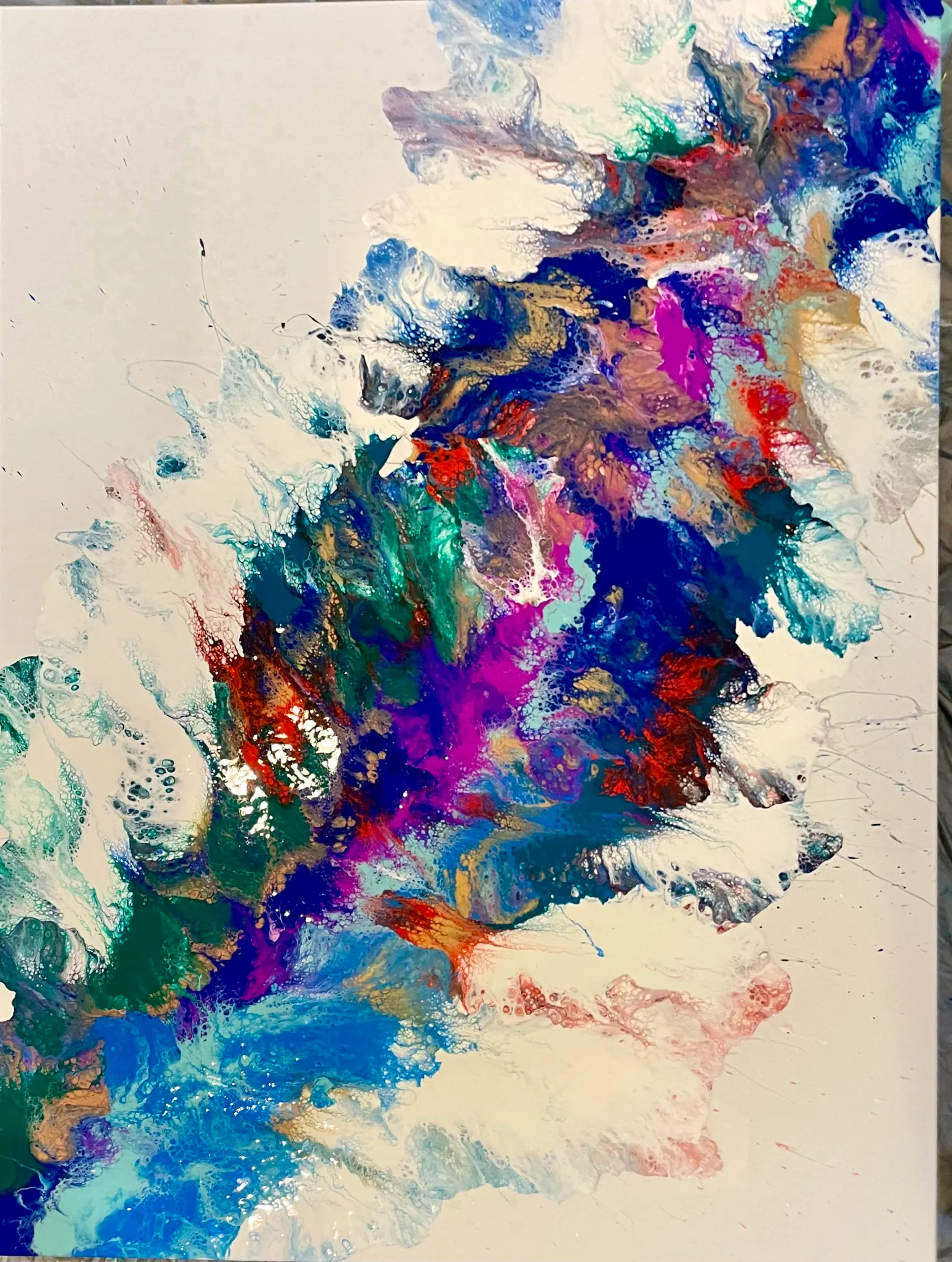 An abstract poured painting with a diagonal band of royal blue, purple, green and rust feathering out across a white canvas.